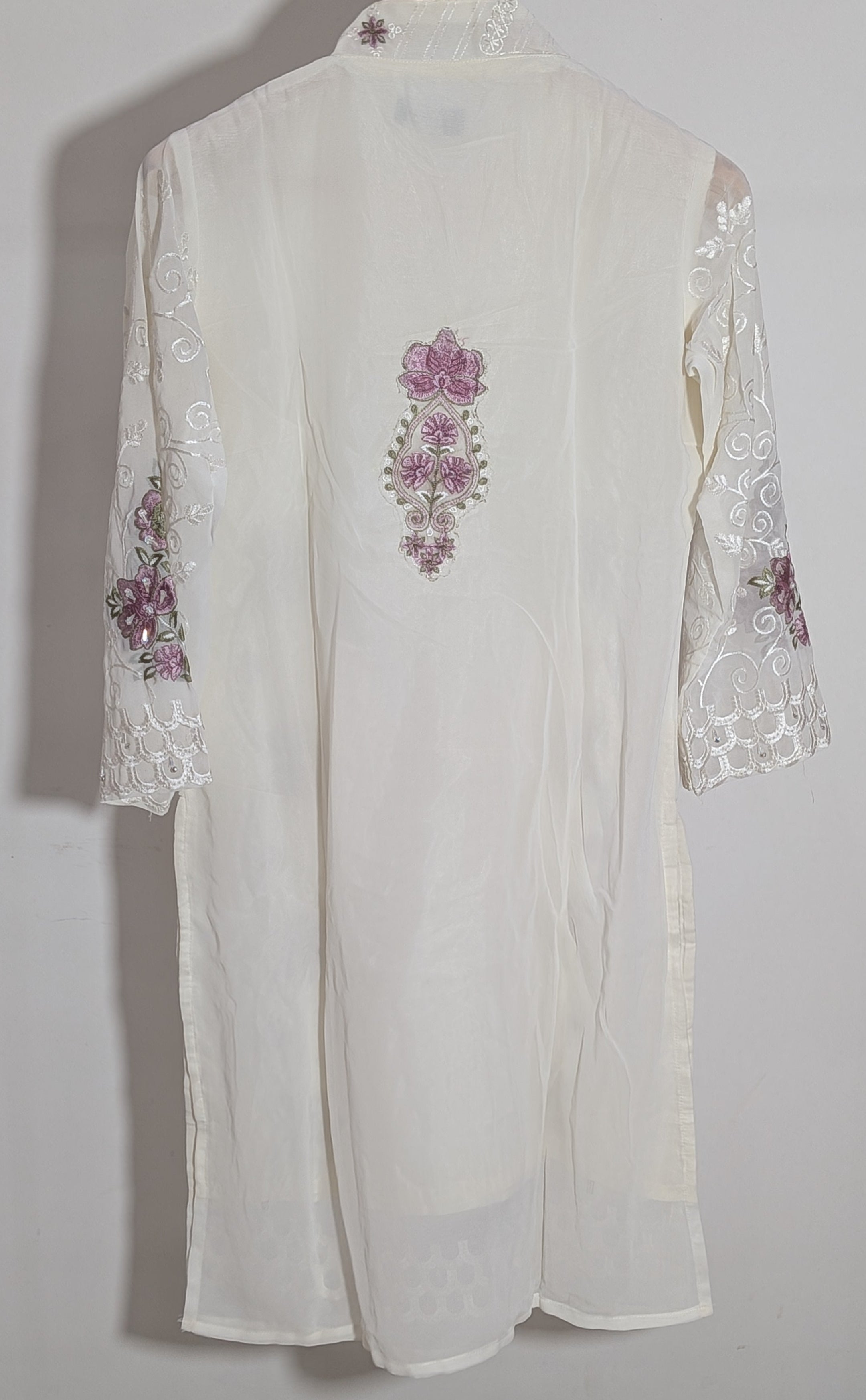 White embroidered garment on a wooden hanger against a white background