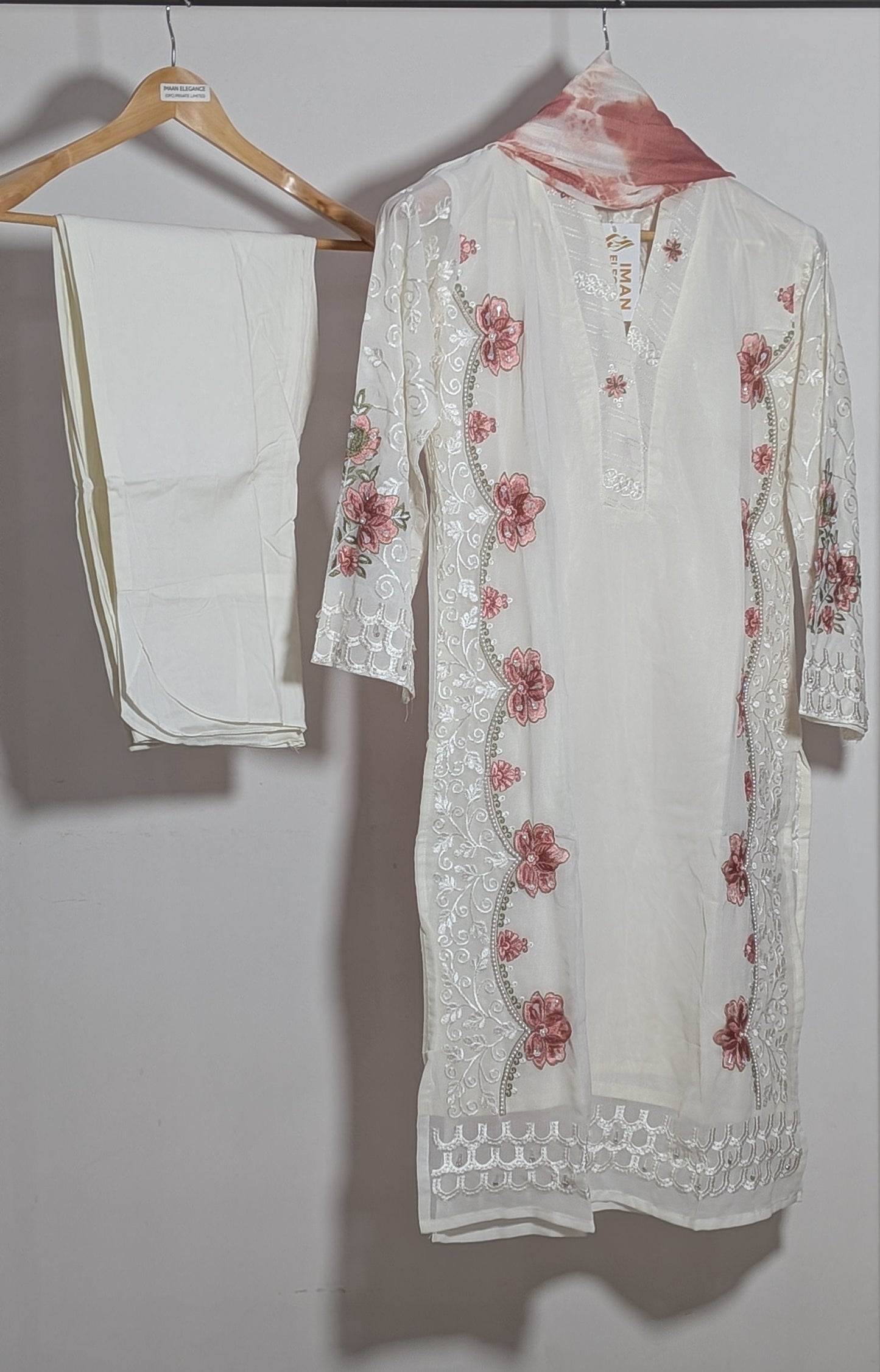 White embroidered kurta with red floral patterns on a hanger against a plain background