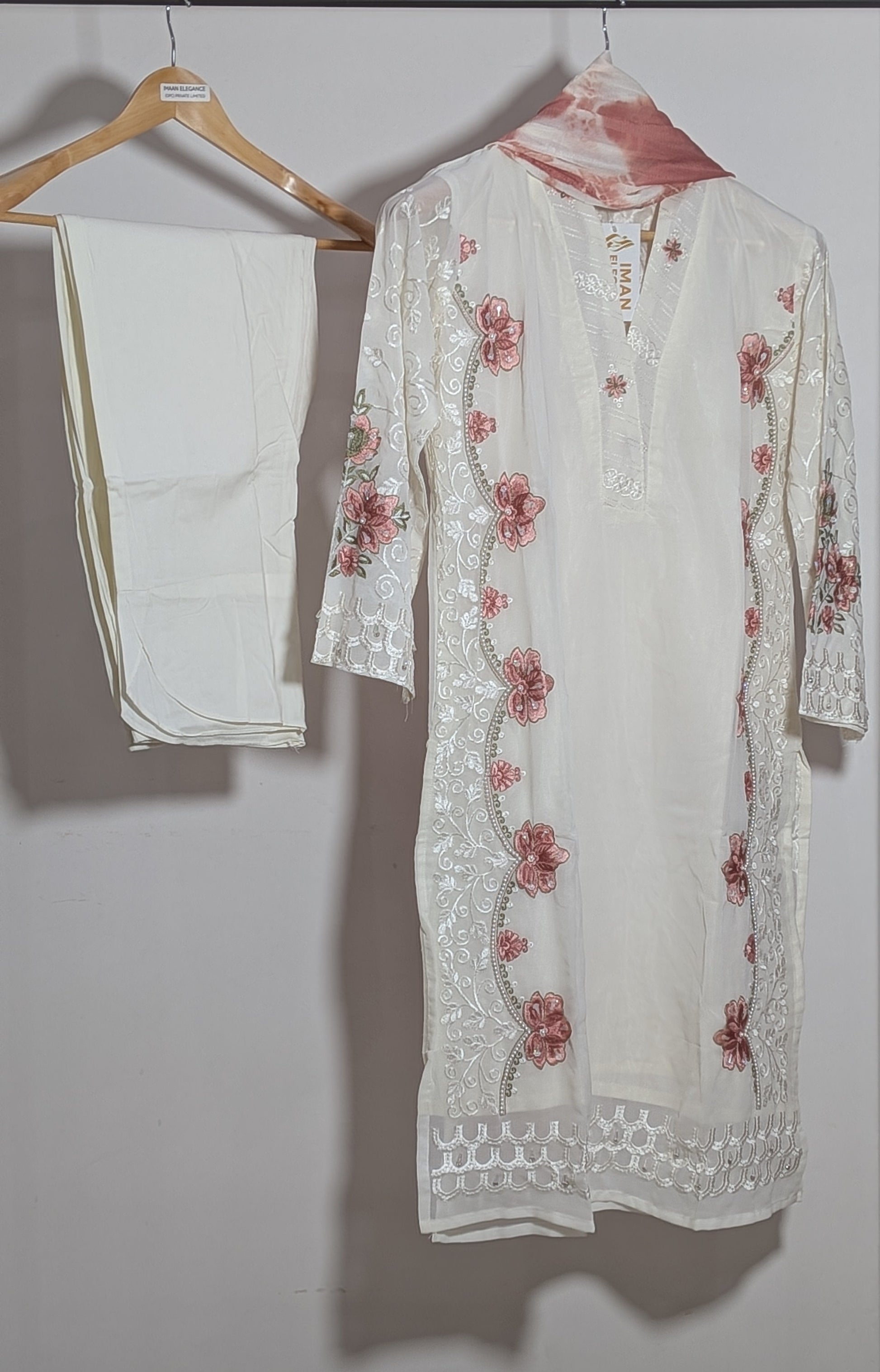 White embroidered kurta with red floral patterns on a hanger against a plain background