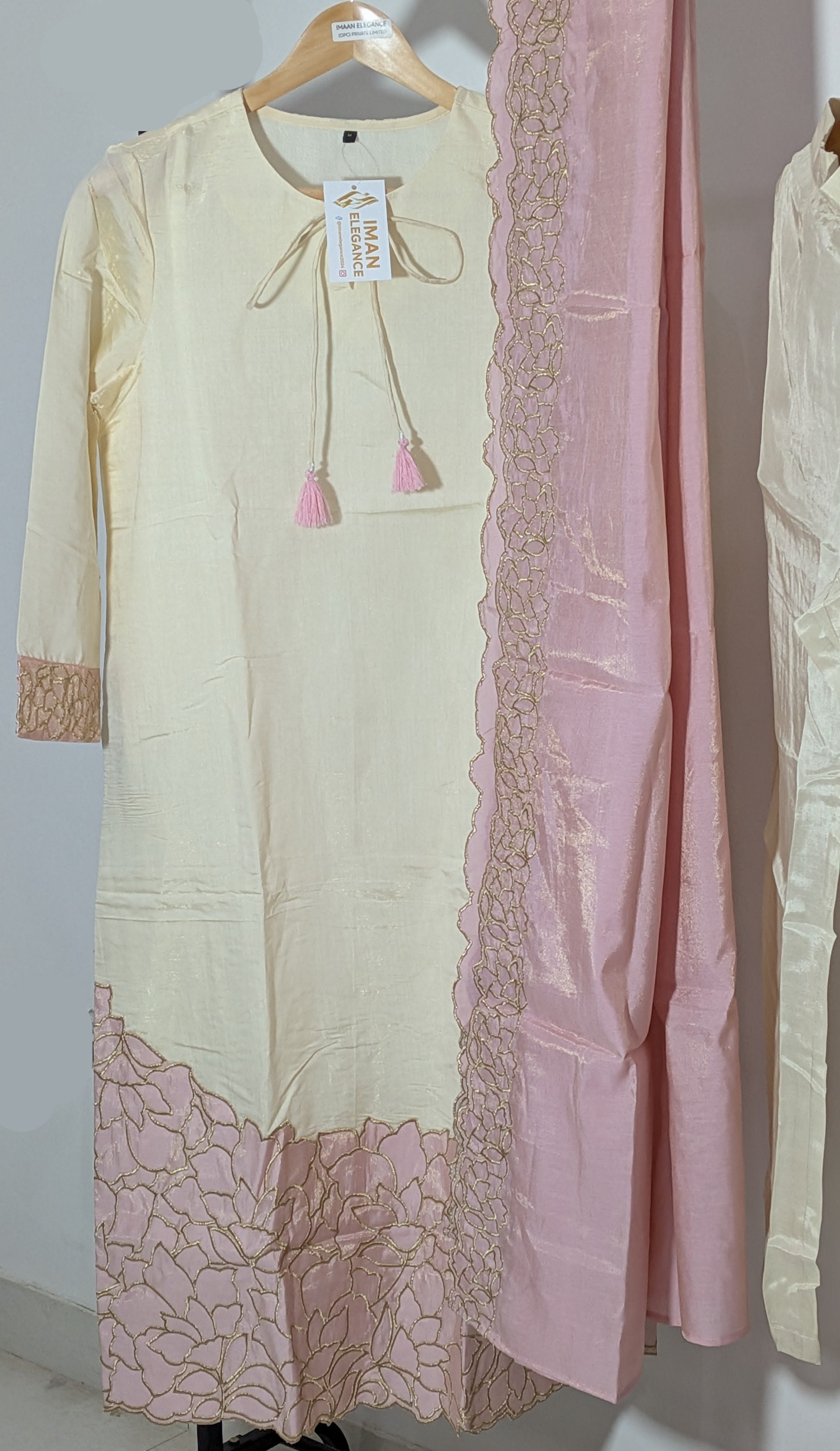 Light-colored dress with lace details on a hanger against a neutral background