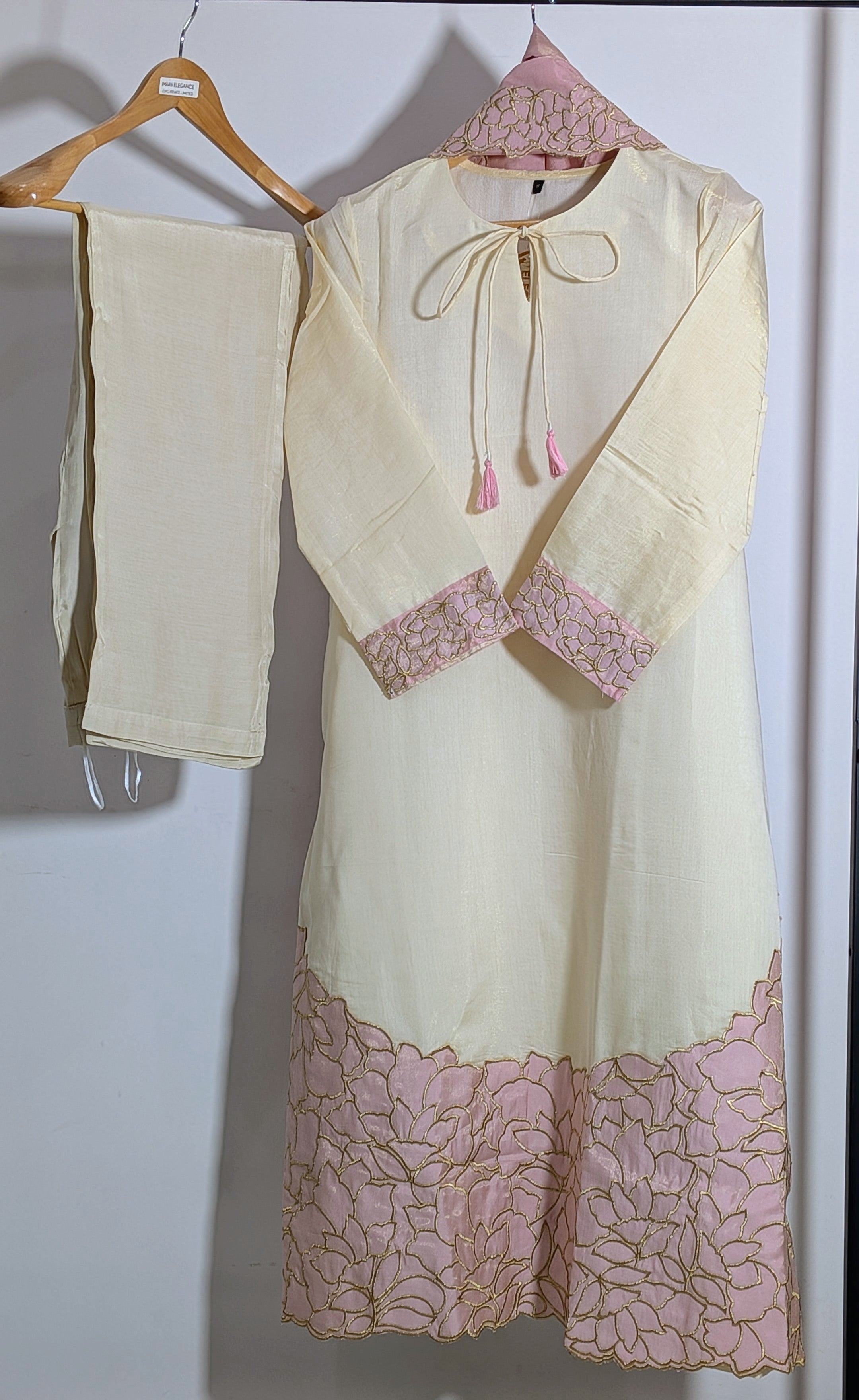 White dress with pink lace details on a hanger against a white background