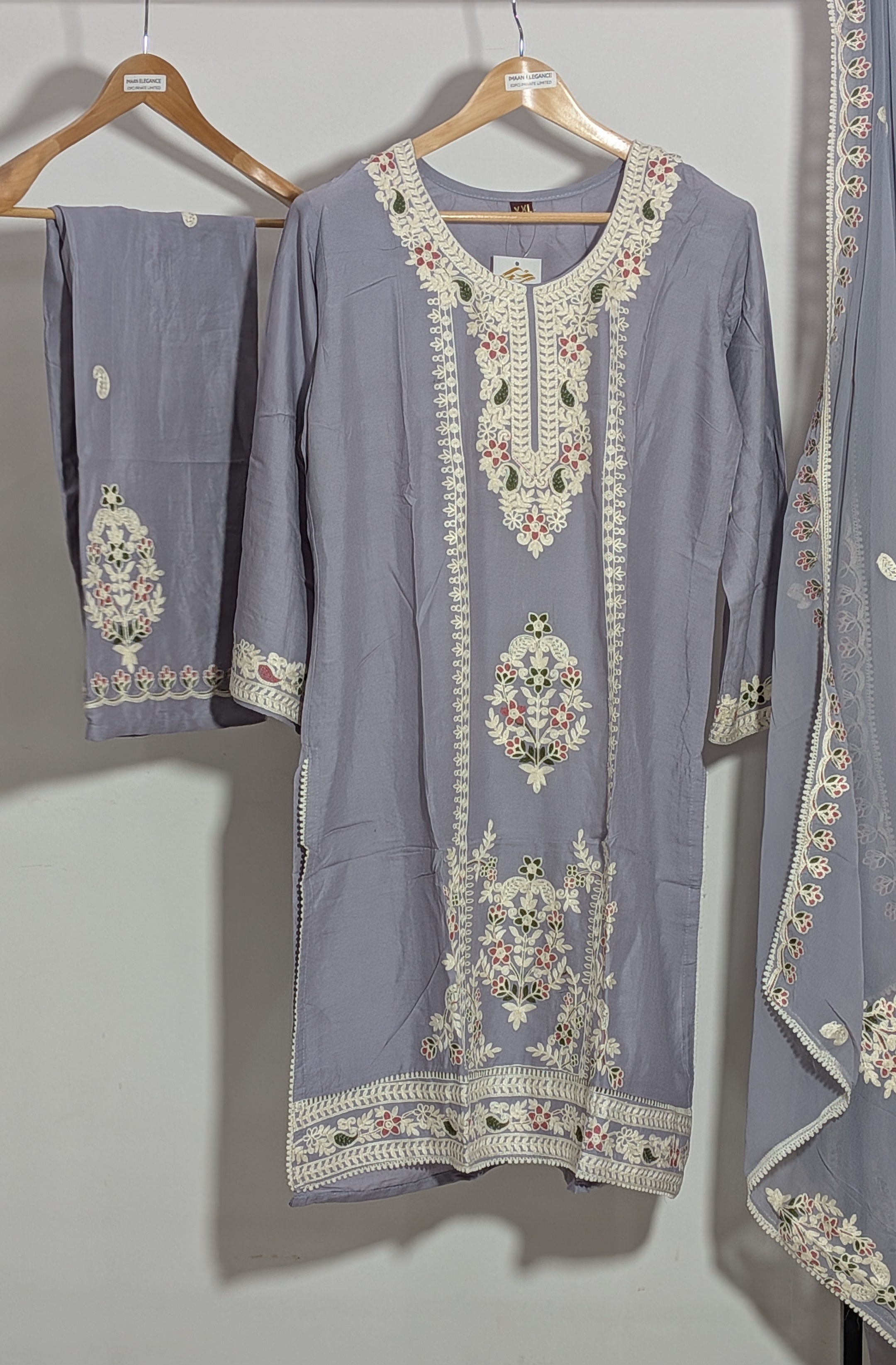 Gray embroidered traditional outfit on a hanger against a white background