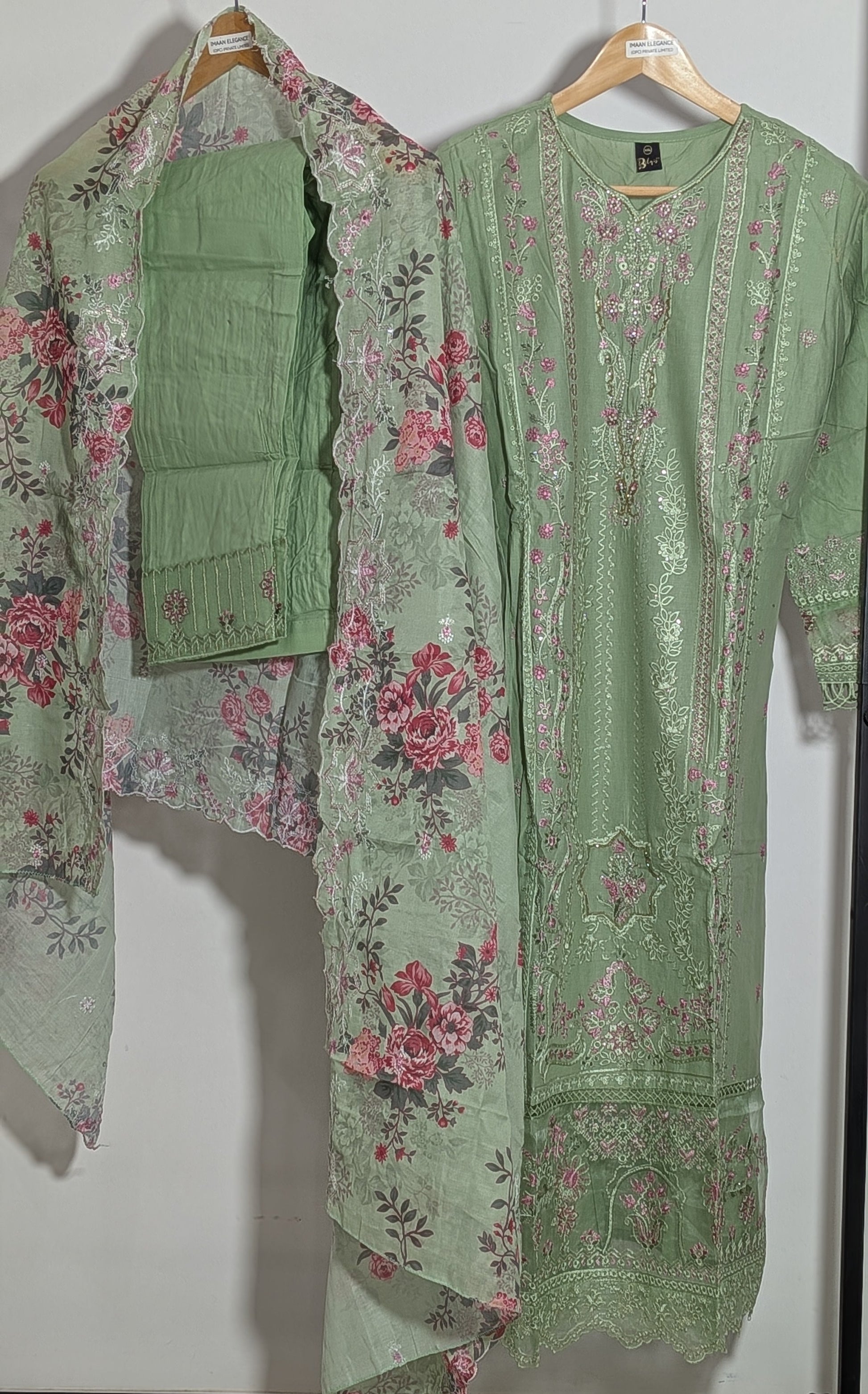 Green floral outfit on hangers against a white wall