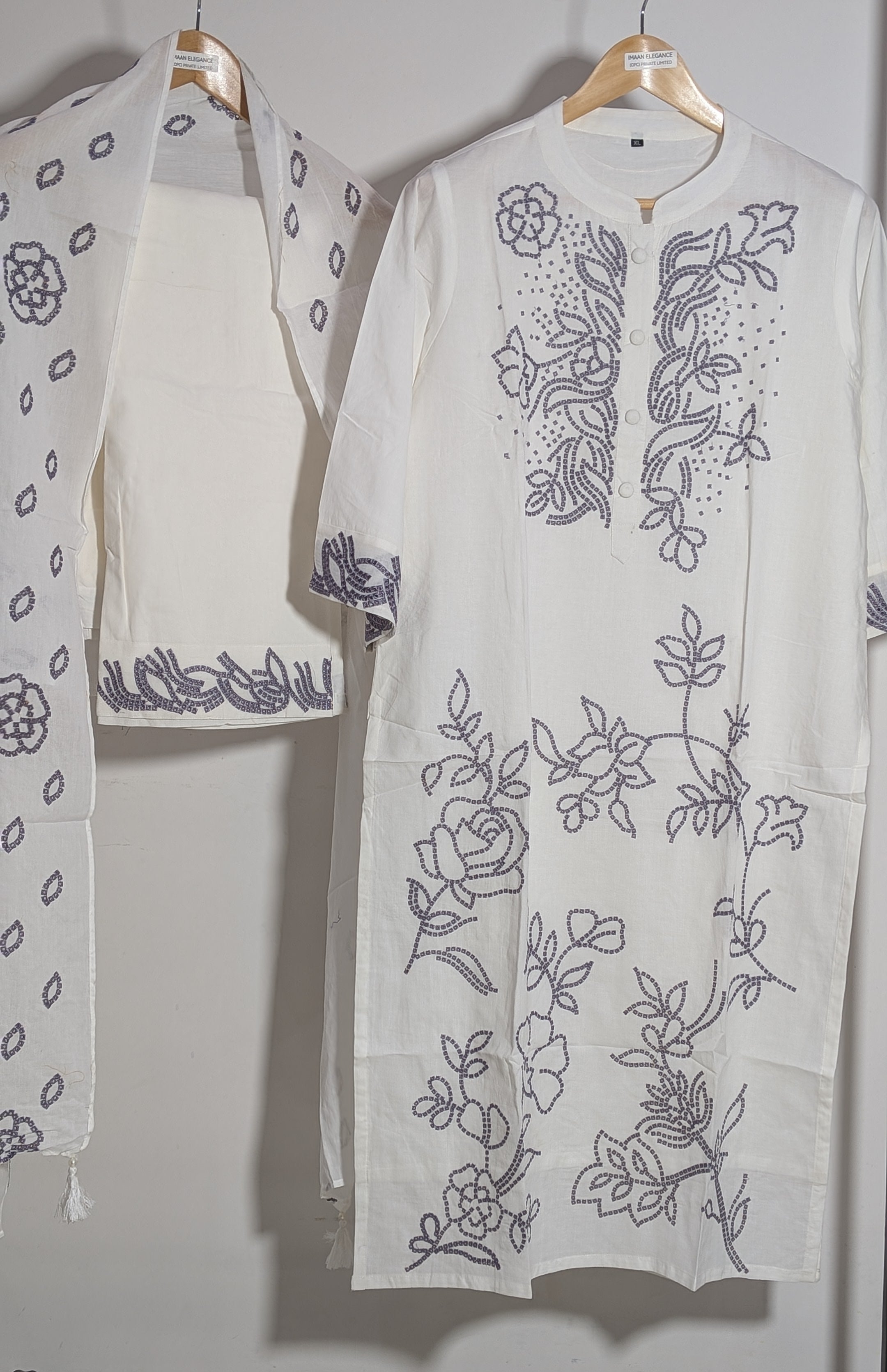 White embroidered garment on a hanger against a white background