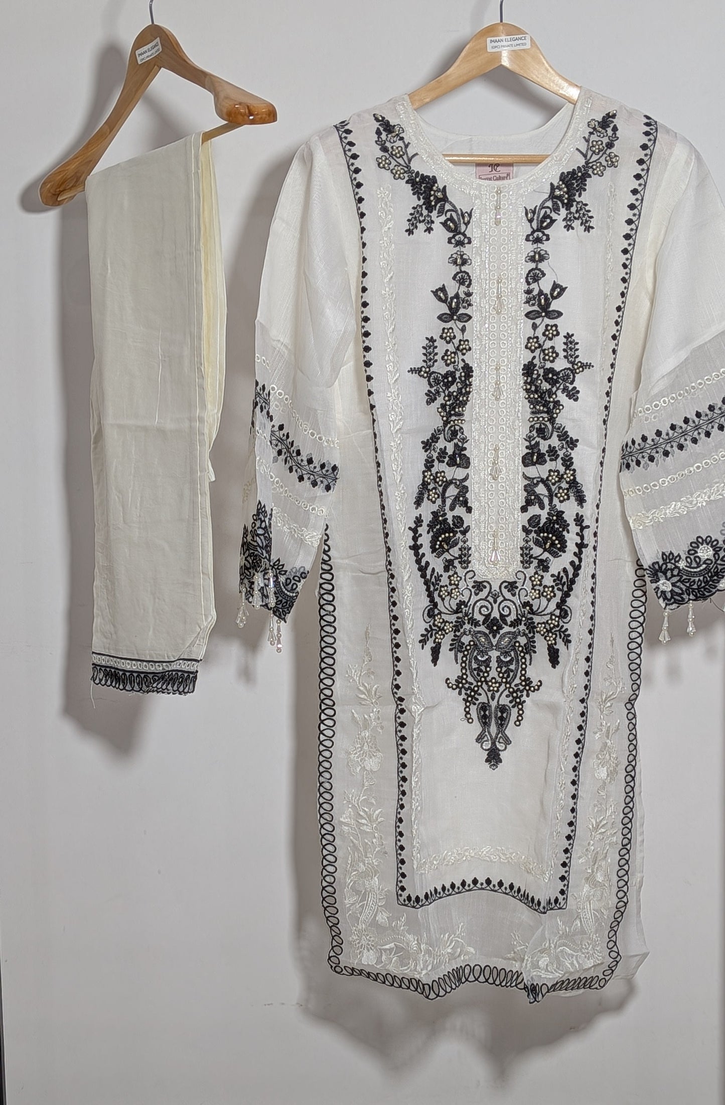 White embroidered kurta with black patterns on hangers against a white background