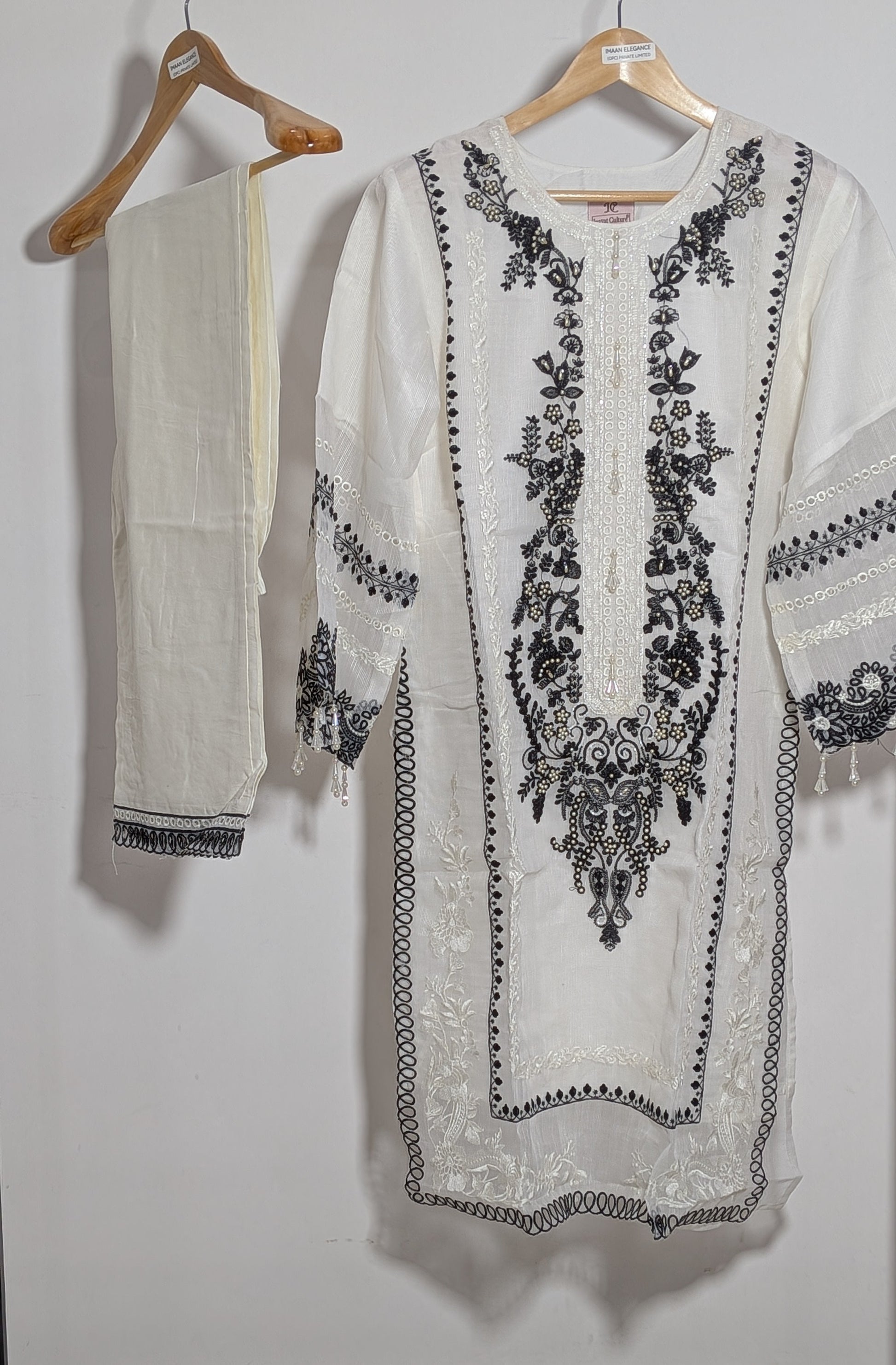 White embroidered kurta with black patterns on hangers against a white background