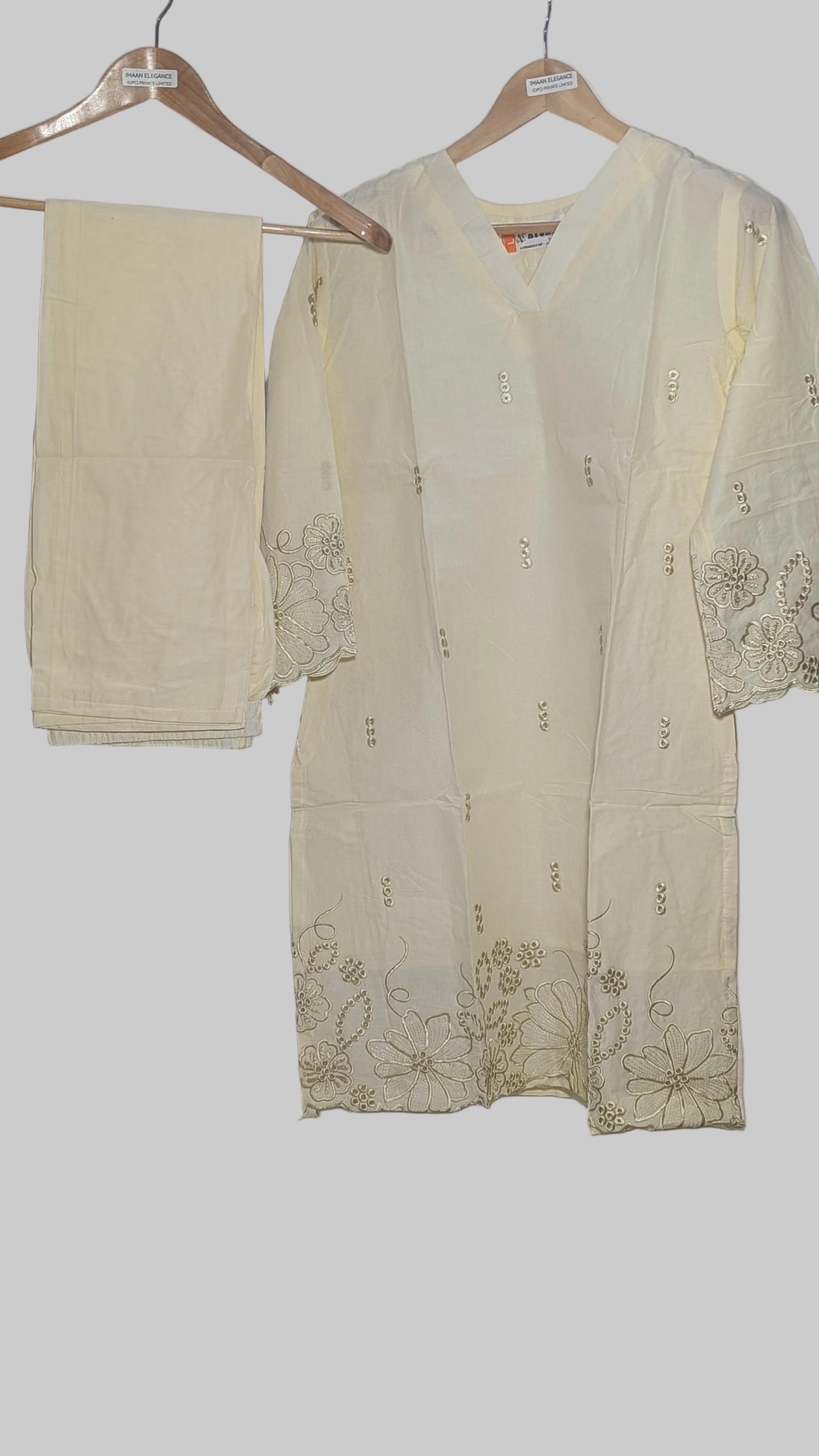 Light-colored traditional outfit with floral embroidery on a white background