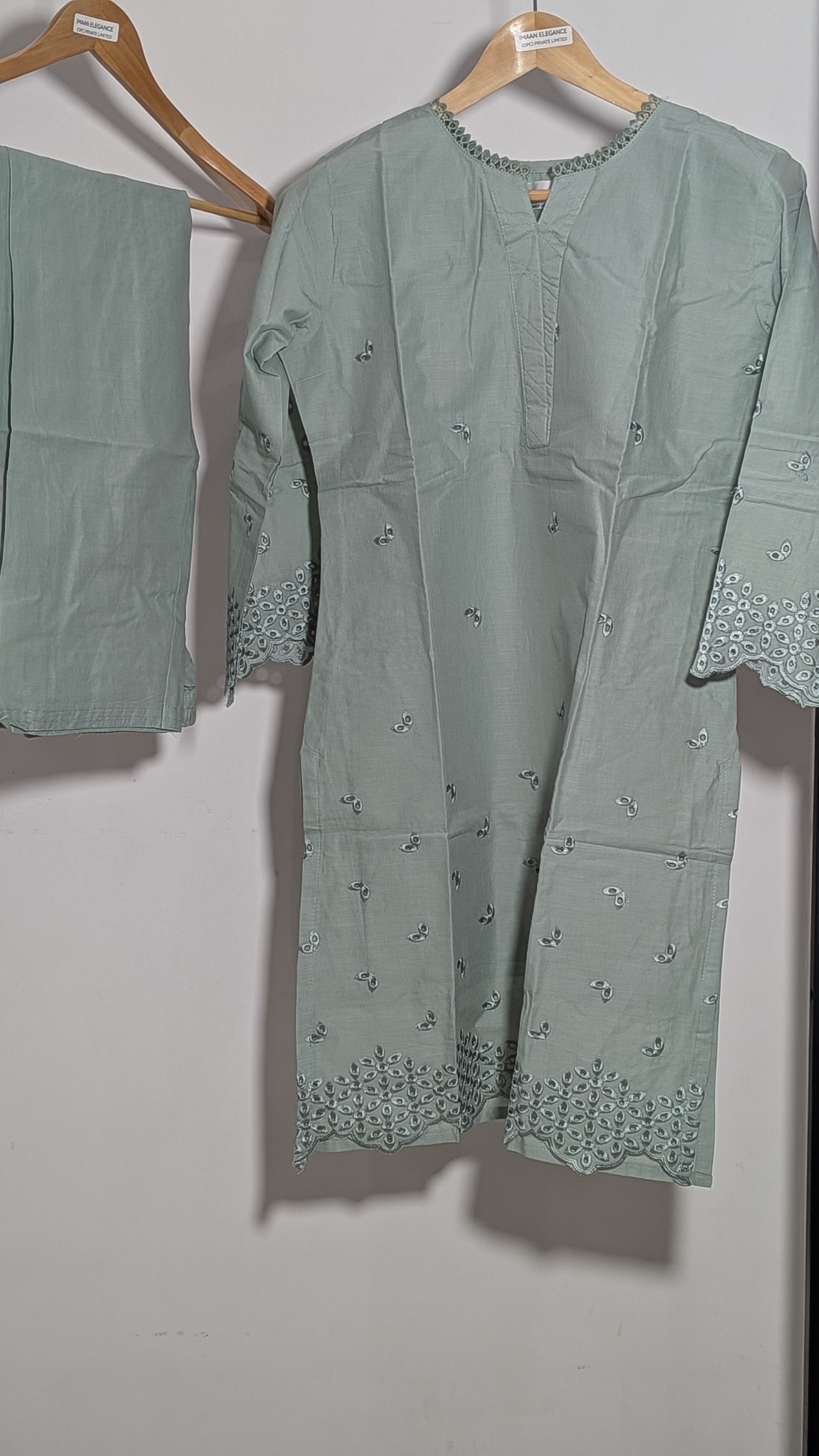 Green embroidered outfit on a hanger against a plain background