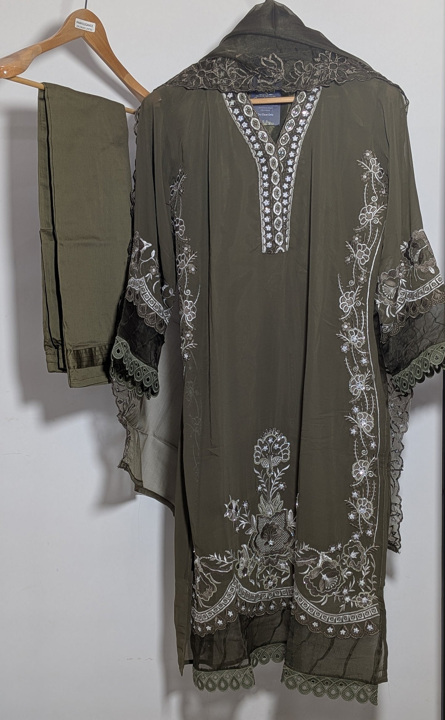 Green embroidered traditional outfit on a hanger against a white background