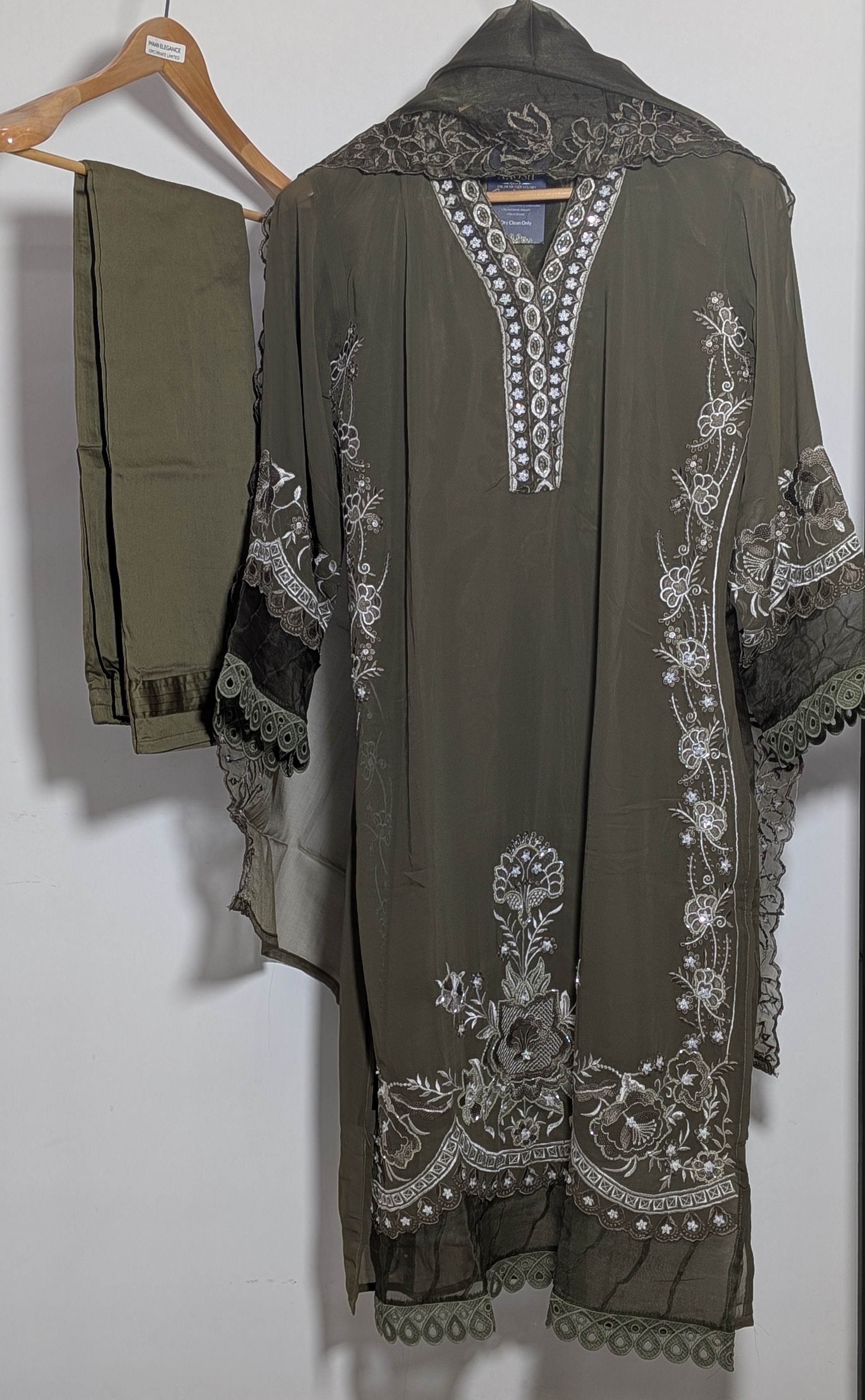 Green embroidered traditional outfit on a hanger against a white background